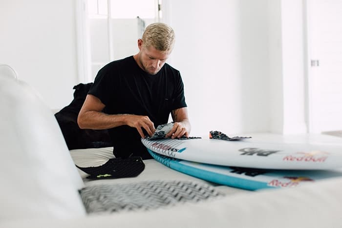 mick fanning attaching a tail pad to his surfboard
