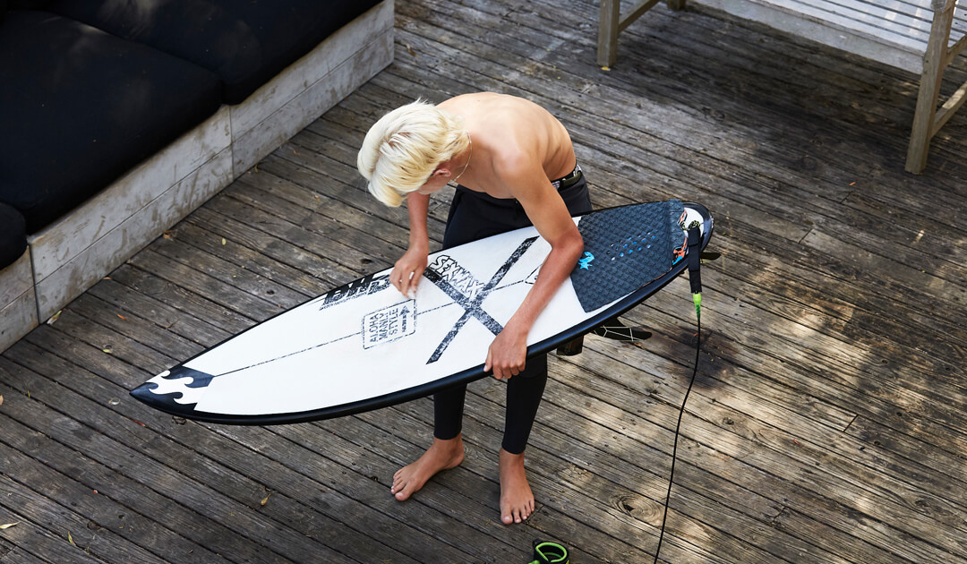 Grom waxing a DHD surfboard